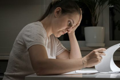 Portrait of stessed woman feeling frustrated while reading documents of divorce. Concept of